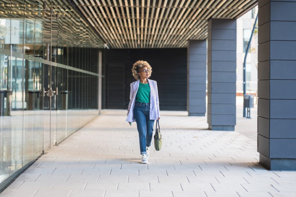 Confident black business woman walking in office district smiling empowered African American female